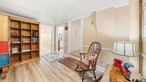 A spacious living room with a wooden bookshelf, a rocking chair, and a lamp. - Twin Fawns 2 Bedroom Cabin (Estes Park)