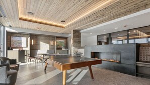 Un espacio interior moderno con mesa de ping pong, zona de estar y chimenea.