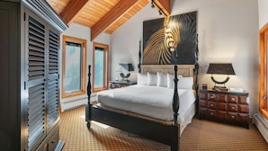 A bedroom with a four-poster bed, wooden ceiling beams, a large abstract painting, a nightstand with a lamp, and a dresser. - Family-friendly Ski Escape With Hot Tub 4 Bedroom Condo (Park City)