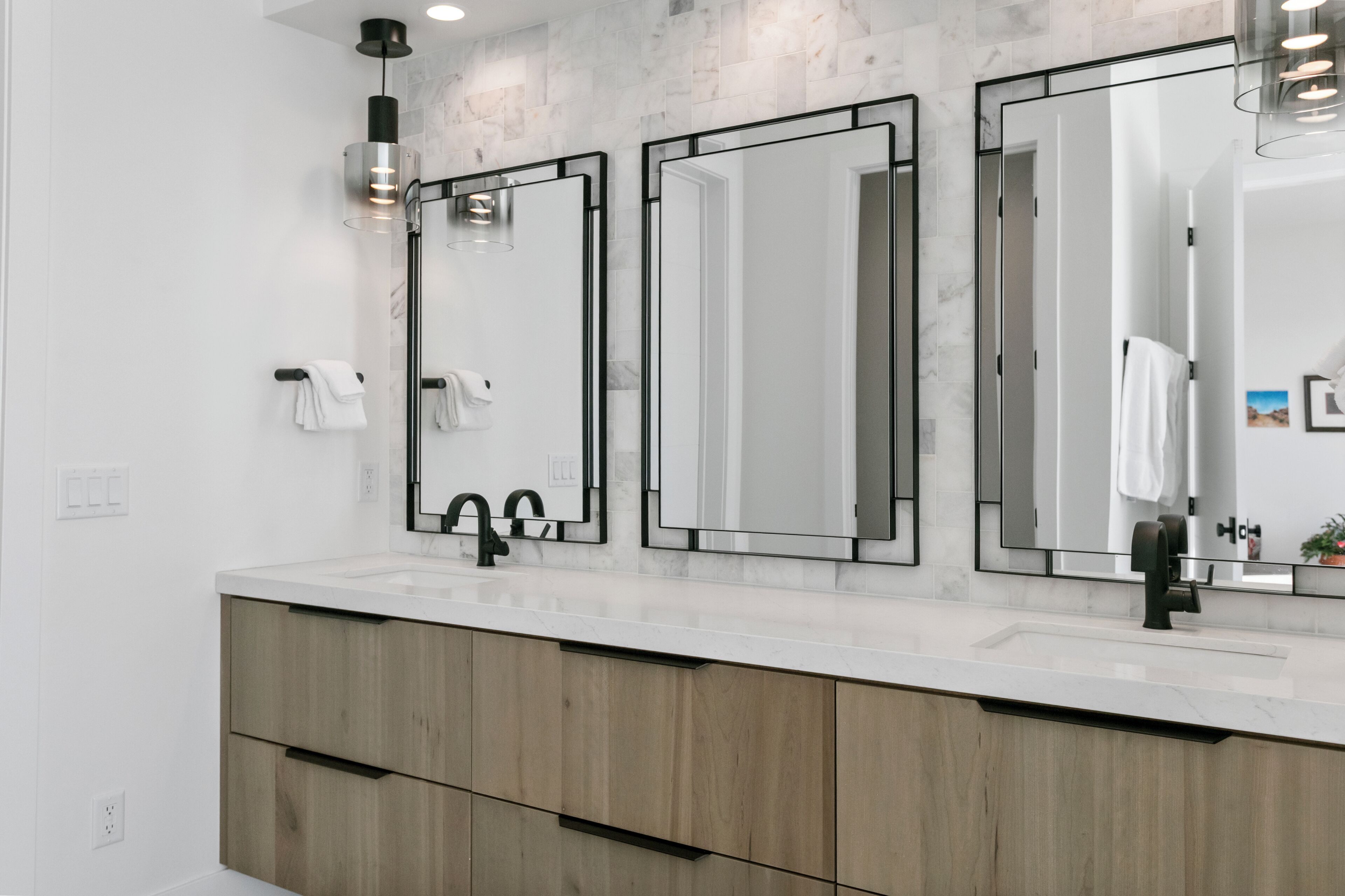 A modern bathroom with a large mirror, a sink, and wooden cabinets.