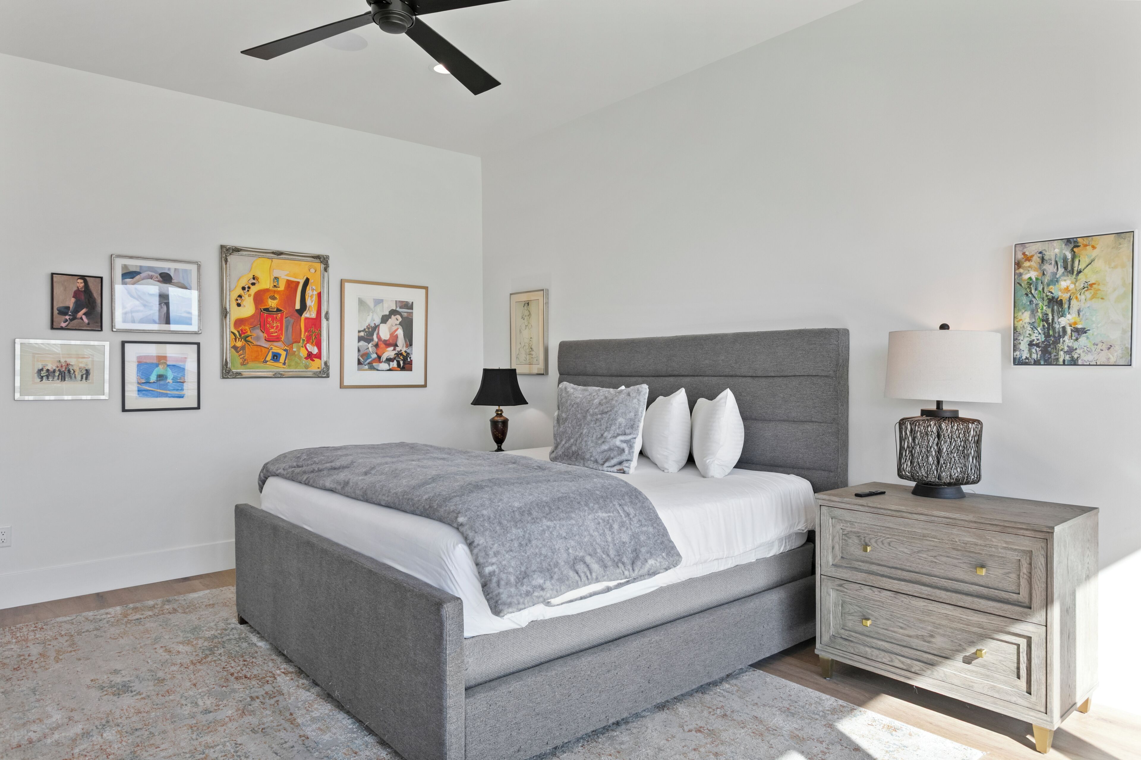 A bedroom with a bed, bedside tables, and artwork on the walls.