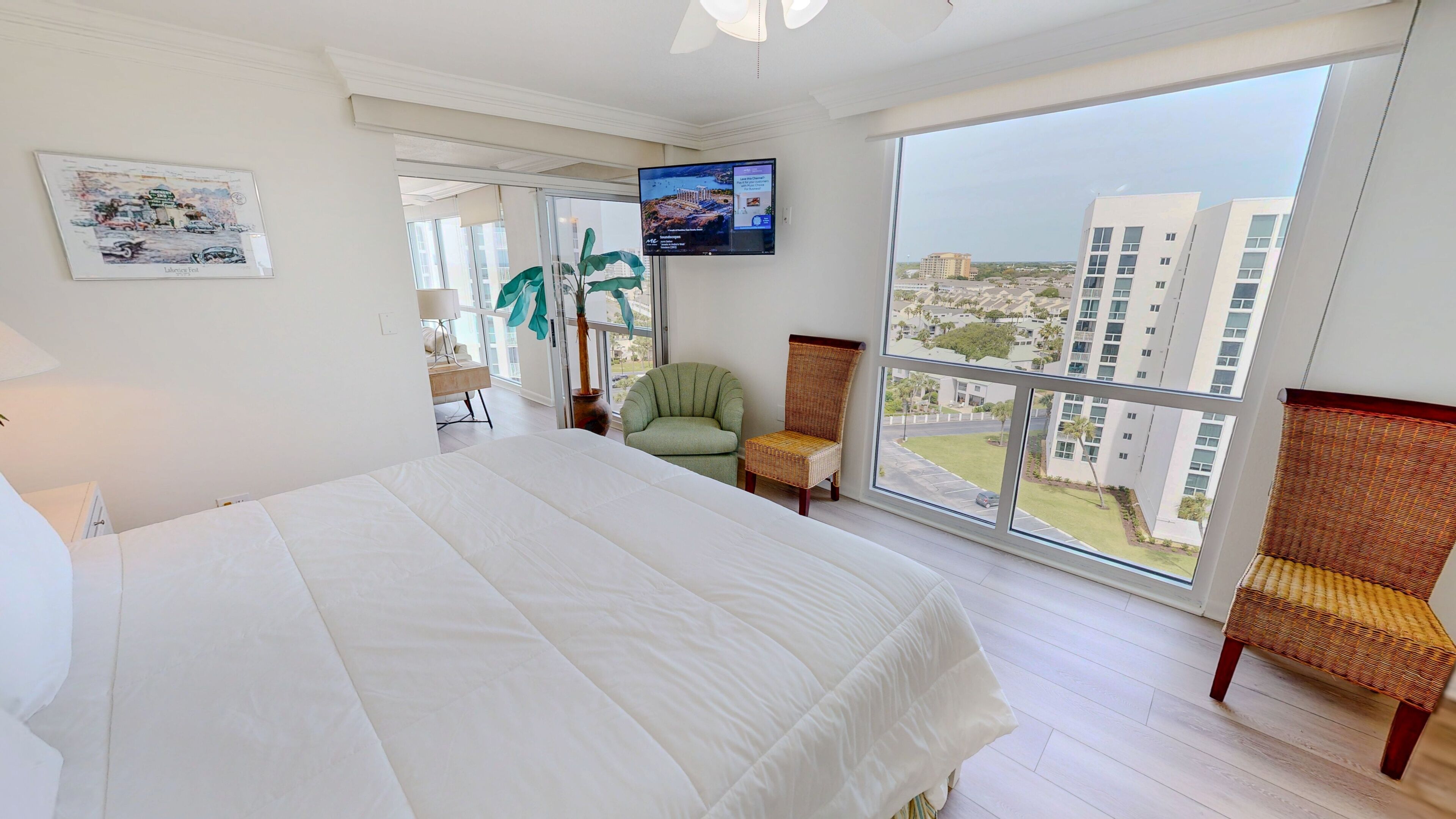 Habitación de hotel con una cama grande, televisión, vistas a edificios y una silla.