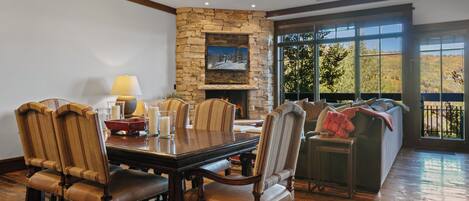 A dining area with a stone fireplace, a large window with a view, and a cozy seating area.