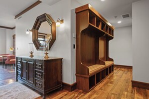 A wooden bench with a cushioned seat and backrest, a large mirror with a hexagonal frame, and a dark wooden cabinet with drawers and a lamp on top. - Ski In/ski Out Mid-mountain Getaway 2 Bedroom Condo (Park City)