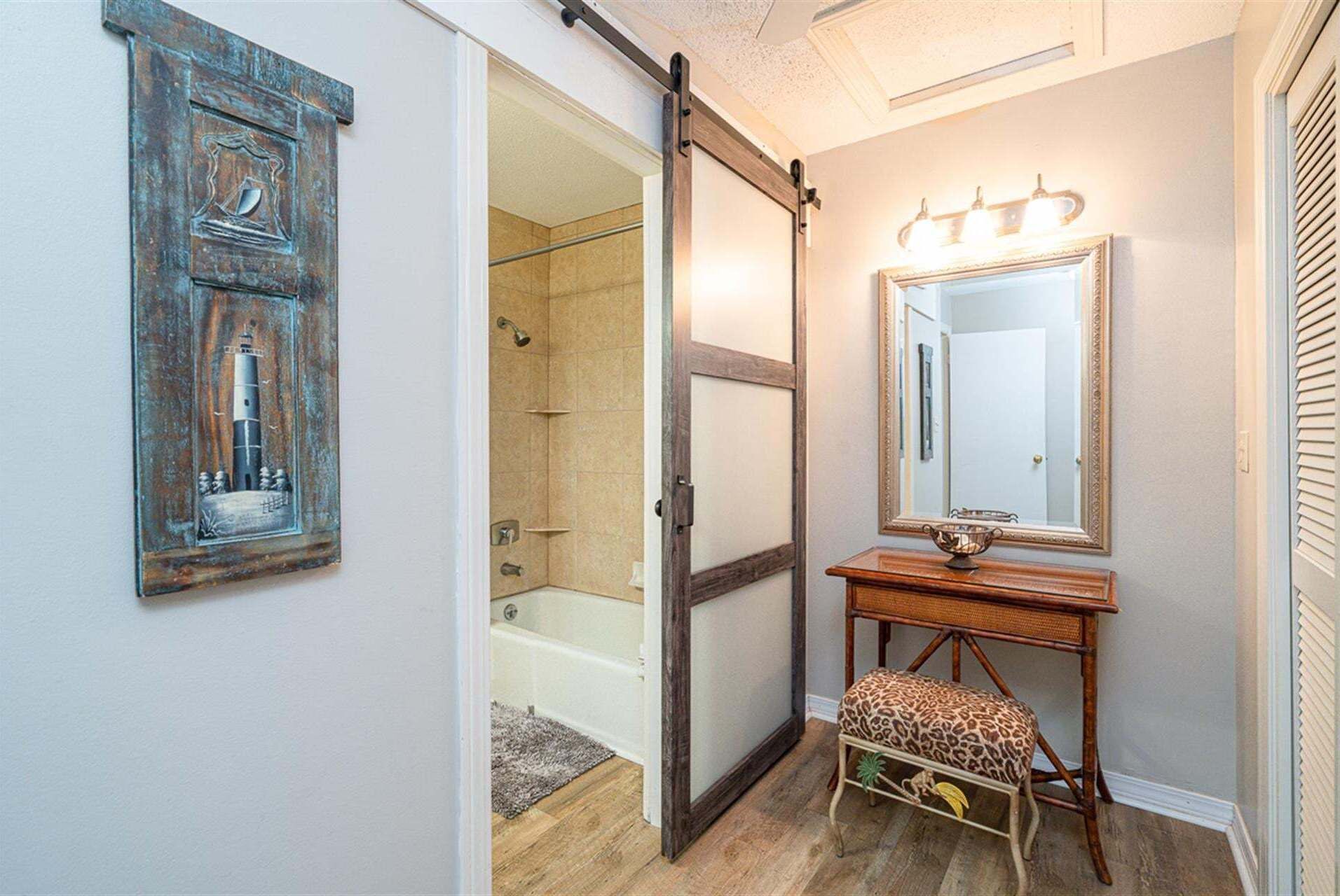 Une salle de bain avec une douche à l’italienne, un meuble-lavabo en bois avec un miroir et un tabouret à motif léopard.