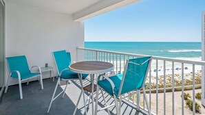 A balcony with a table and chairs, overlooking a beach with a clear view of the ocean. - Shoreline Towers 1095 2 Bedroom Condo (Destin)