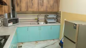 Une cuisine avec des armoires de couleur turquoise, un four à micro-ondes et un réfrigérateur.