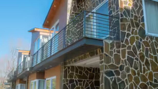 Un immeuble à plusieurs étages, doté d’une façade en pierre et d’un balcon avec des balustrades en métal.