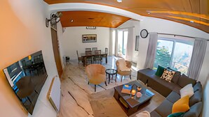 Un salon moderne doté d’un téléviseur à écran plat, d’un canapé et d’un coin repas avec une table et des chaises.