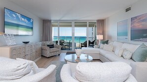 A spacious living room with a large balcony overlooking the ocean, furnished with a sofa, chairs, and a coffee table. - Shoreline Towers 3095 2 Bedroom Condo (Destin)