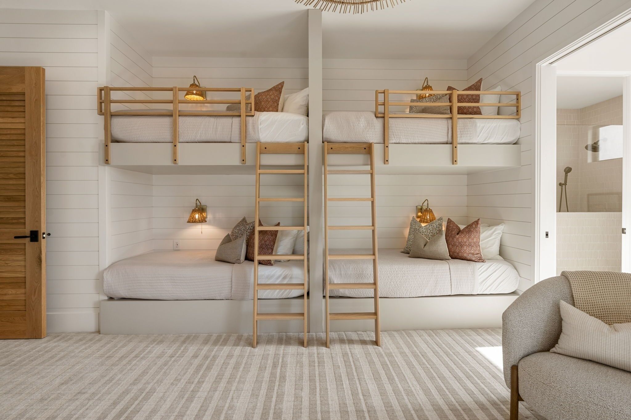 A bunk bed room with a ladder, a sofa, and a chair.