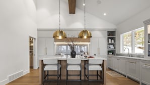Cozinha moderna com ilha central, iluminação pendente e vista para o exterior.