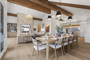 A spacious dining area with a wooden table and chairs, a chandelier, and a stone accent wall. - Sun Ridge Vista 4 Bedroom Home (Park City)