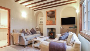 Una sala de estar acogedora con chimenea, sofás, una mesa de centro y televisor.