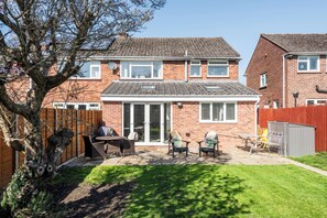A two-story house with a patio, outdoor furniture, and a tree. - Stylish Cheltenham Home, 4 Bed, Garden & Parking (Cheltenham)