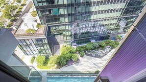 Un edificio moderno de gran altura con fachada de vidrio, jardín en la azotea y piscina.