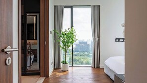 Una habitación de hotel moderna con un ventanal grande, una planta en maceta y una cama.