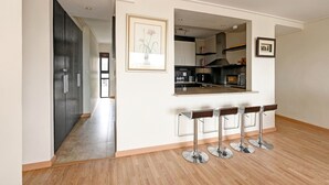 Uma cozinha moderna com uma ilha central, banquetas de bar e um quadro pendurado na parede.