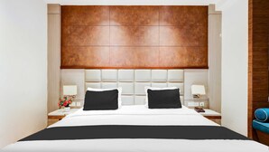 A modern hotel room with a large bed, two bedside tables with lamps, and a wooden headboard.
