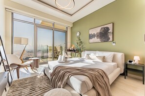 A modern bedroom with a large bed, a view of the city, a desk, and a chair. - Sleek Modern Studio with Direct view of Dubai Skyline - Farhad Azizi Residence, Al Jaddaf (Dubai)