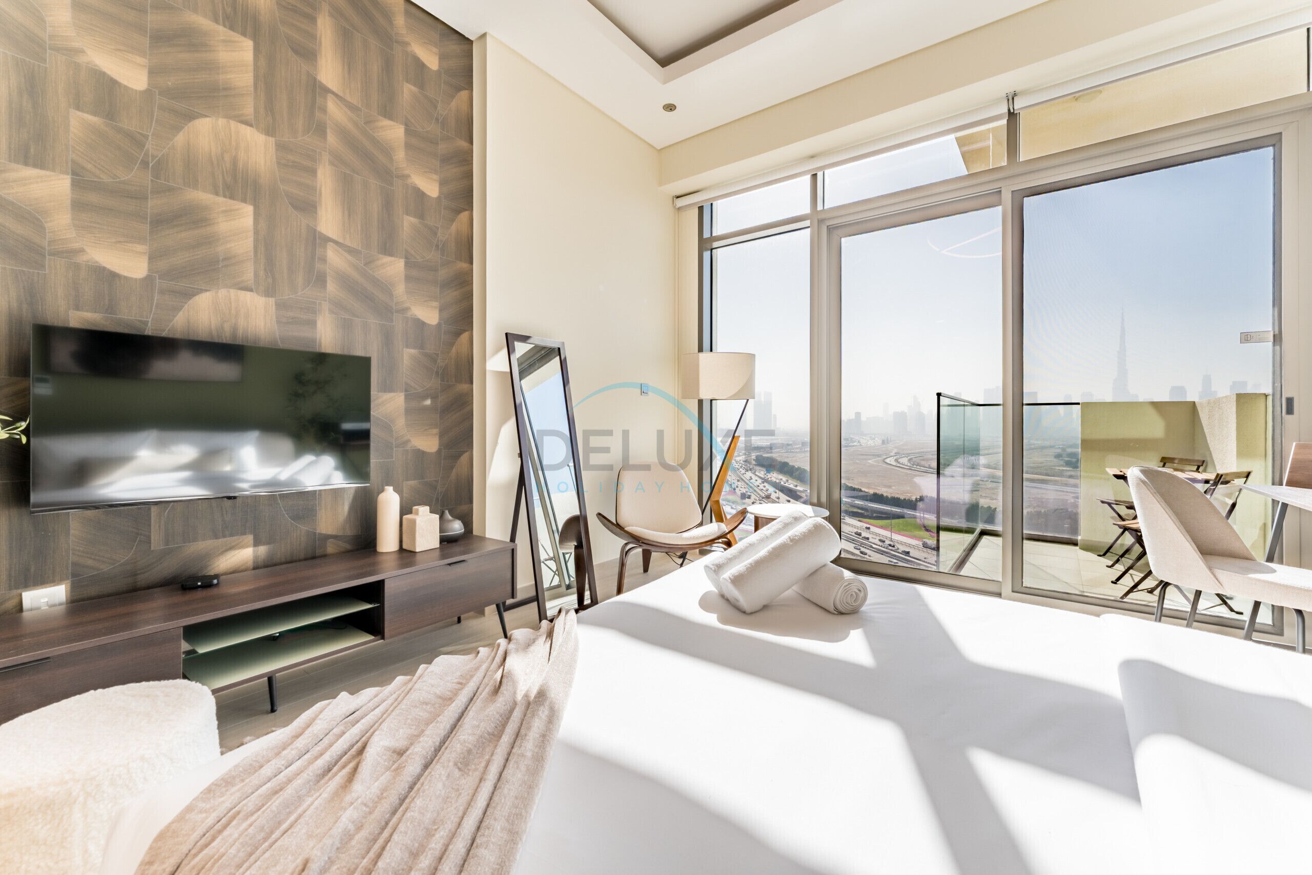 Une chambre d’hôtel moderne dotée d’une grande télévision, d’une table en verre et offrant une vue sur la ville.