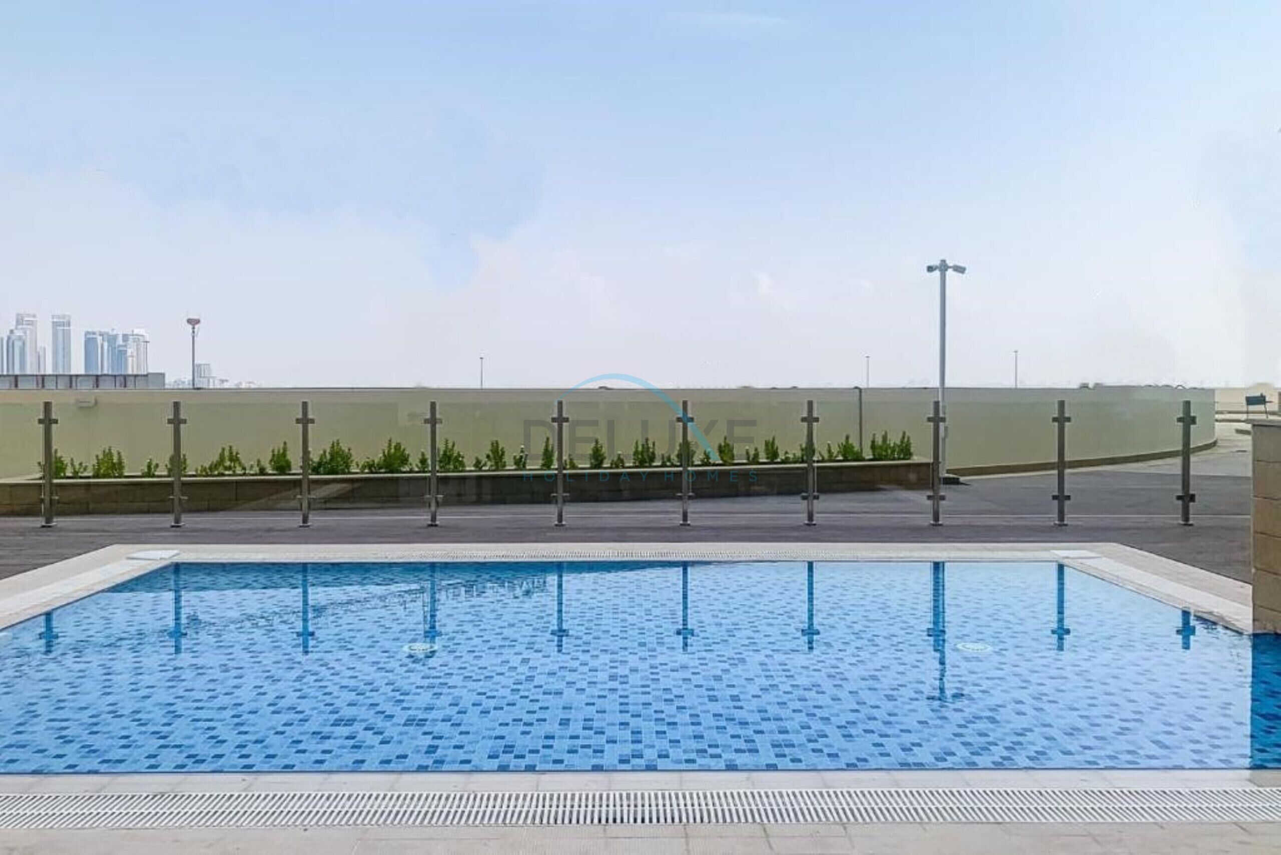 Una piscina con un borde de baldosas y vistas a un horizonte urbano.