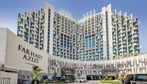 Un immeuble moderne de grande hauteur, doté d’une façade angulaire distinctive, portant l’inscription « FARHAD AZIZI RESIDENCE ».