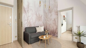 Una sala de estar moderna con un sofá gris, una mesa de centro redonda de madera y un jarrón decorativo.