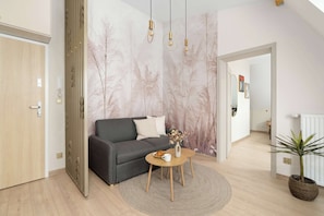 A modern living room with a grey sofa, a round wooden coffee table, and a decorative vase. - Air-conditioned Apartment | 500 m to Market Square, Place to Work (Poznań)