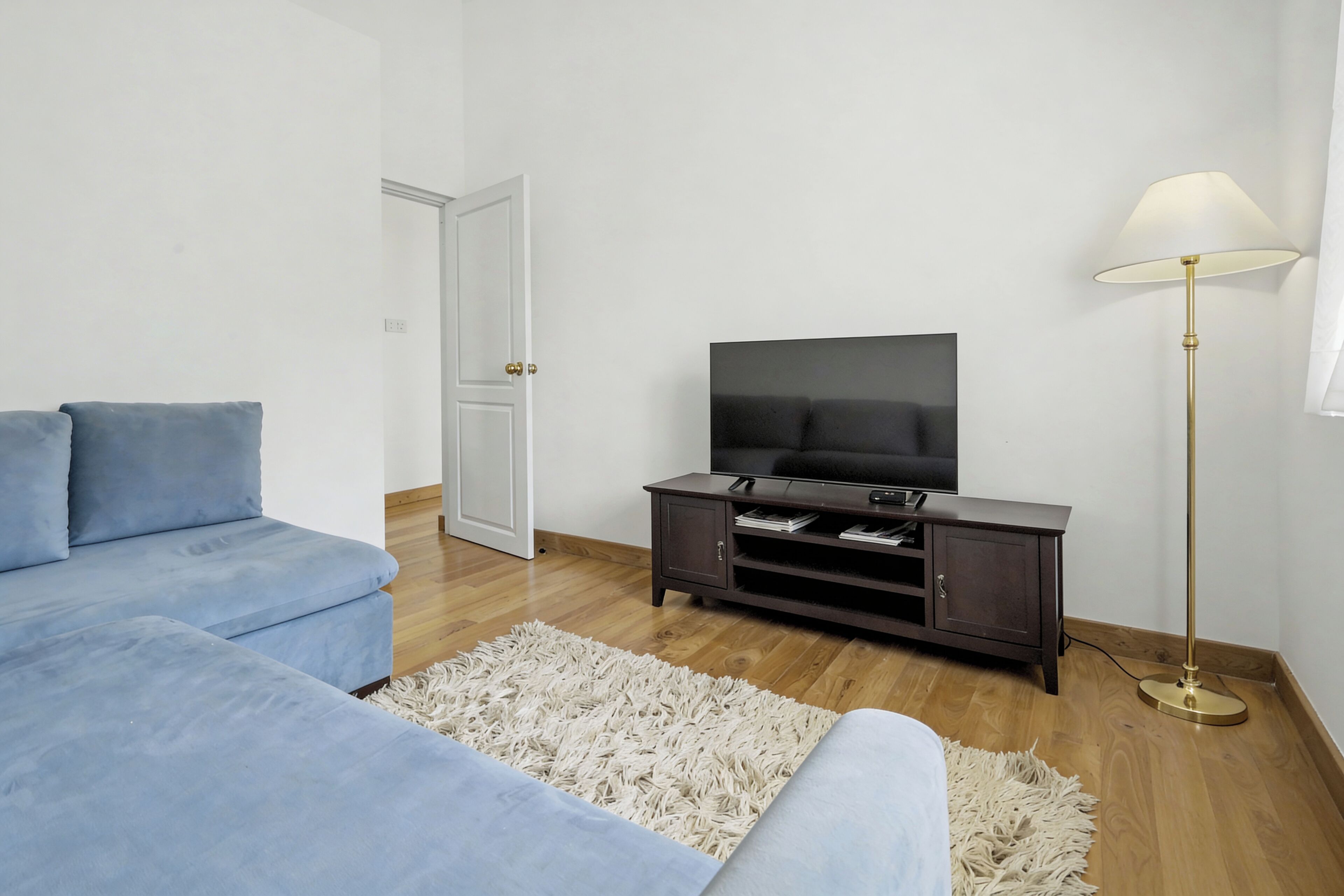 A living room with a sofa, TV, cabinet, and floor lamp.
