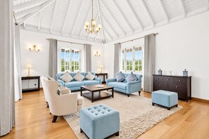 Un salon spacieux avec un plafond haut, un ensemble de canapés, une table basse, une table d’appoint et un meuble.