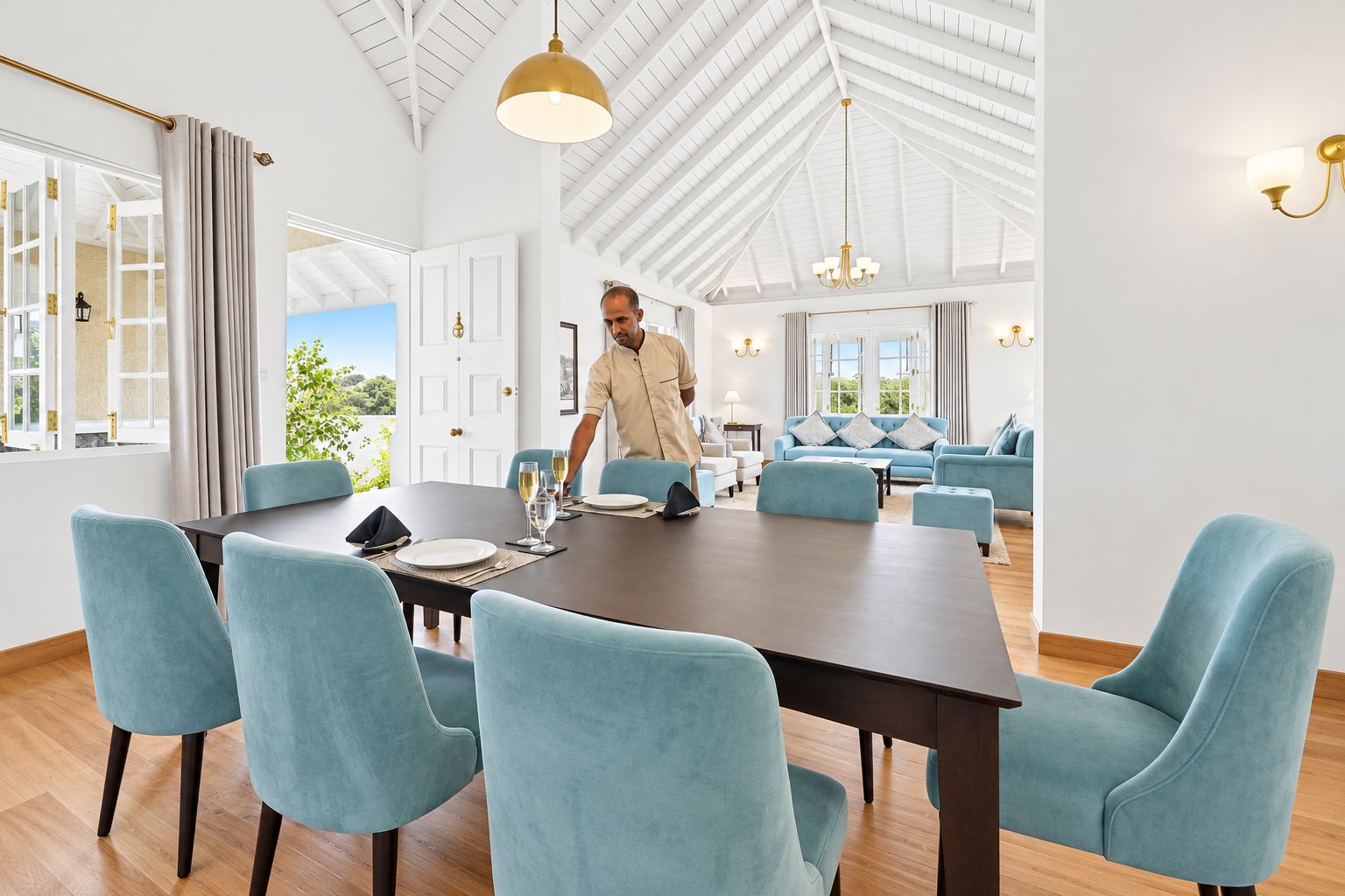 A spacious room with a large dining table, light blue upholstered chairs, and a high ceiling with exposed beams.