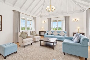 Un salón amplio con techo alto, ventanas grandes y un candelabro.