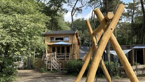 Una cabaña de madera rústica con un porche y un columpio en un área boscosa.