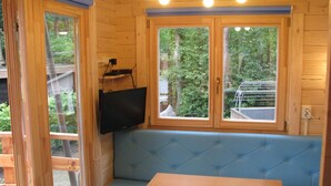 Una cabaña de madera con un banco acolchado azul y una mesa de madera.