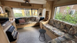 Interior acollidor d'una caravana amb un sofà, una taula petita i una zona de cuina amb graella.