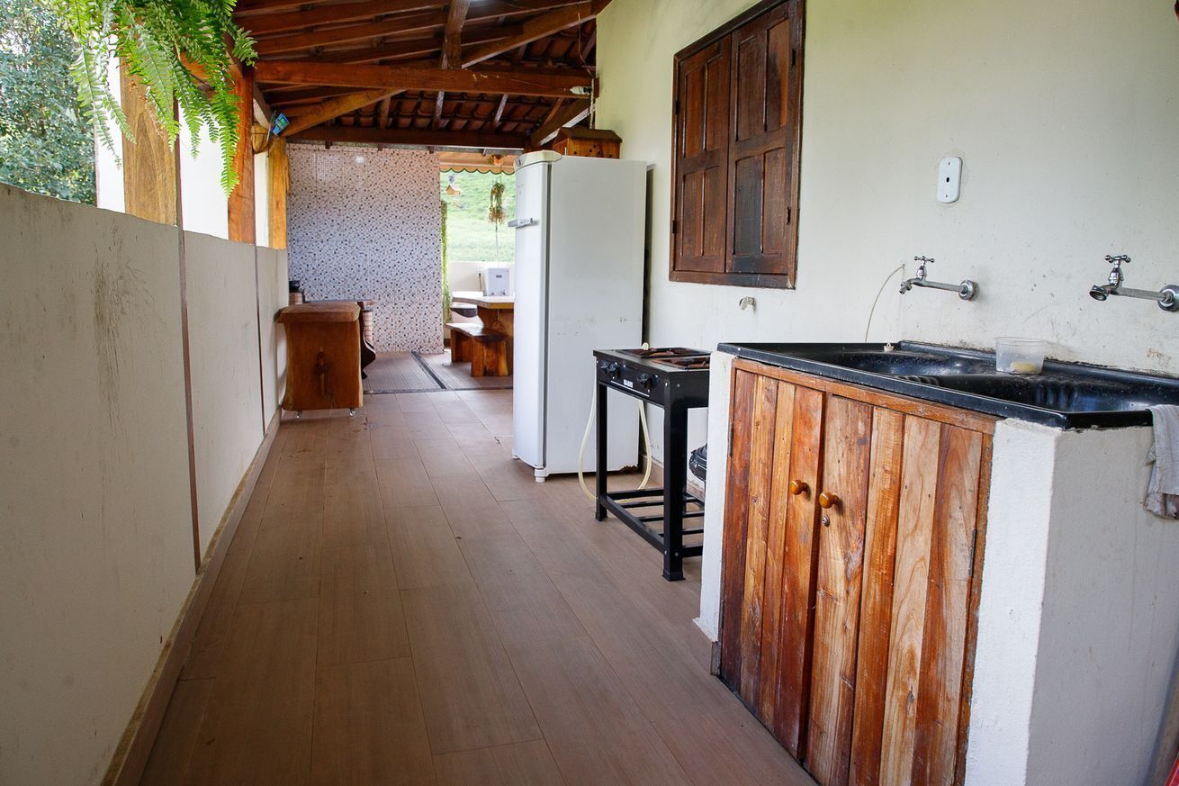 A narrow corridor with a wooden floor, a kitchen area with a stove and sink, and a view into a dining area.