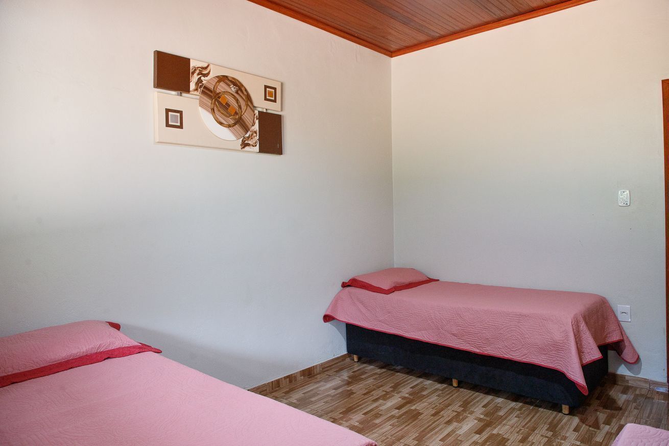 Habitació petita i senzilla amb dos llits, sostre de fusta i una obra d'art penjada a la paret.