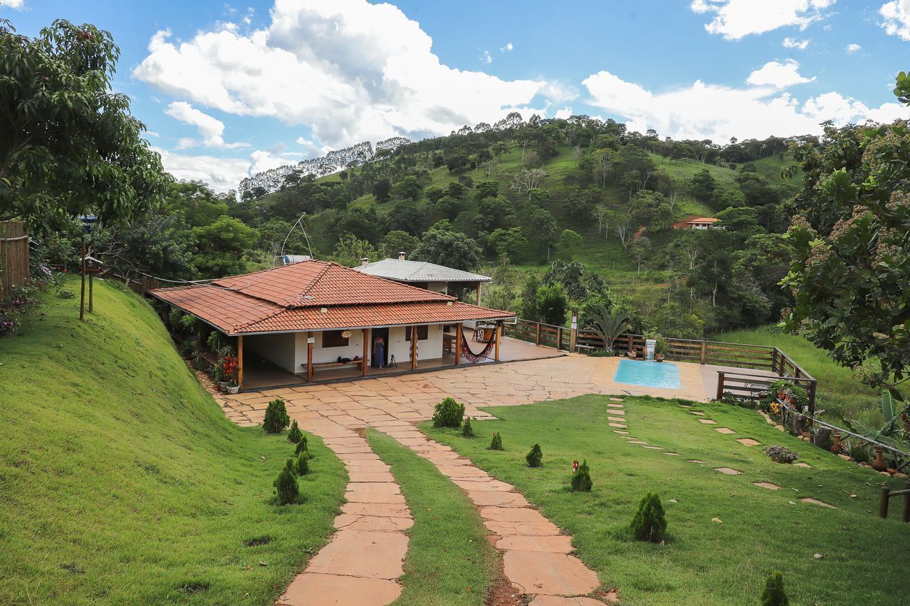 Una casa con techo de tejas rojas, piscina y un camino de piedra que lleva a la entrada.
