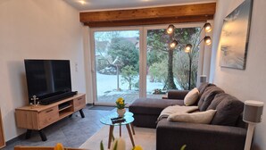 Un salon avec un téléviseur, un canapé et une table basse en verre.