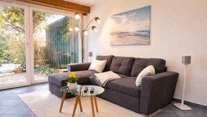 Un salon moderne avec un canapé gris, une table basse en verre et un tableau accroché au mur.