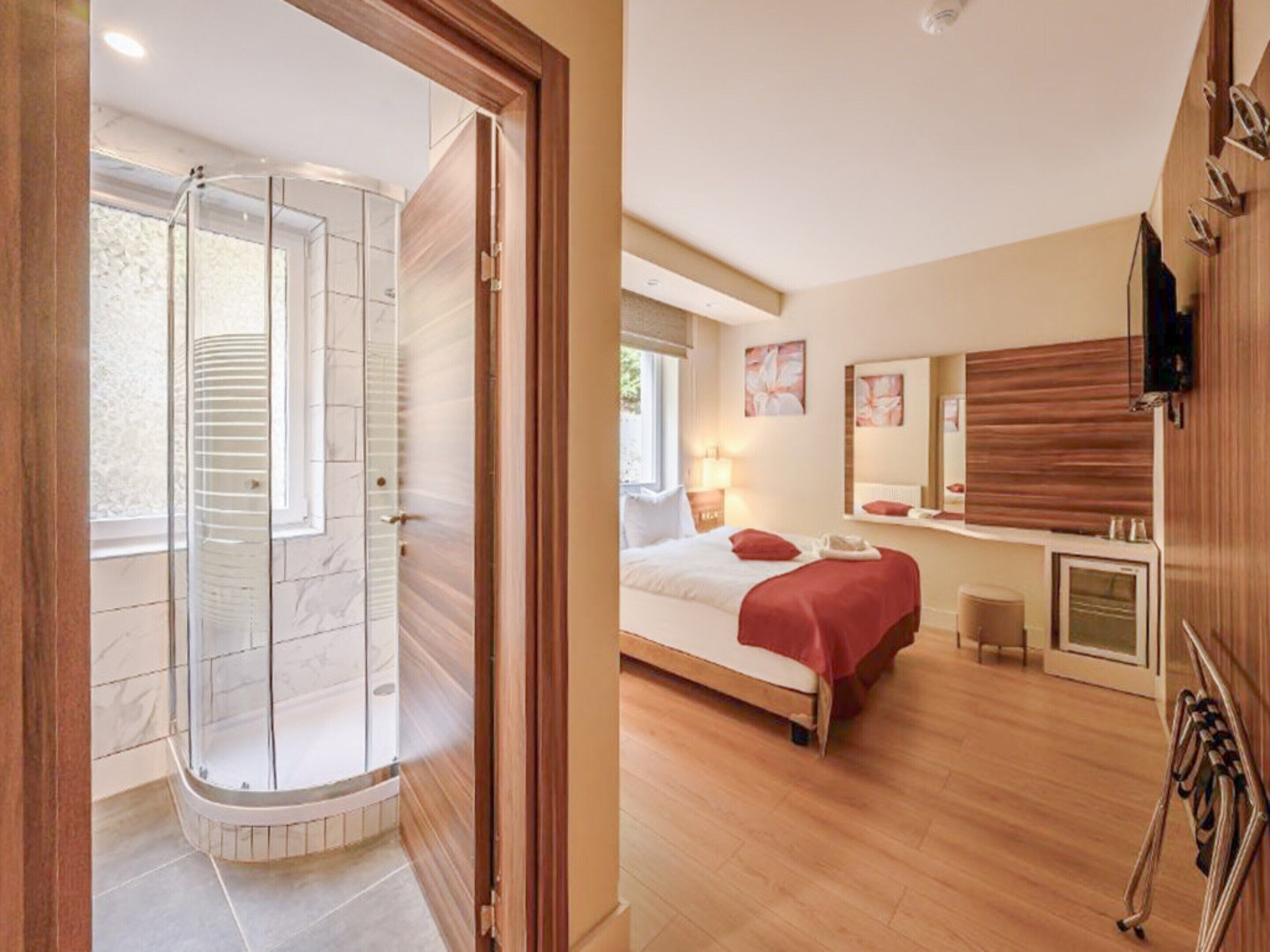 Une chambre d’hôtel équipée d’une douche, d’un lit, d’une table de chevet et d’un grand miroir.