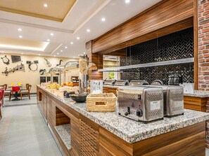 A buffet area with a marble countertop, a coffee machine, and a beverage dispenser.