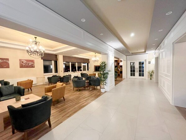 A spacious lobby with a high ceiling, modern furniture, and a large potted plant.