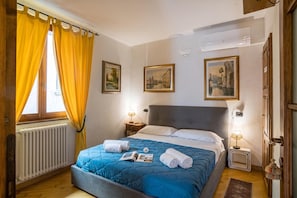 Ein Hotelzimmer mit einem Bett, einem Vorhangfenster, einem Heizkörper und Wandlampen.