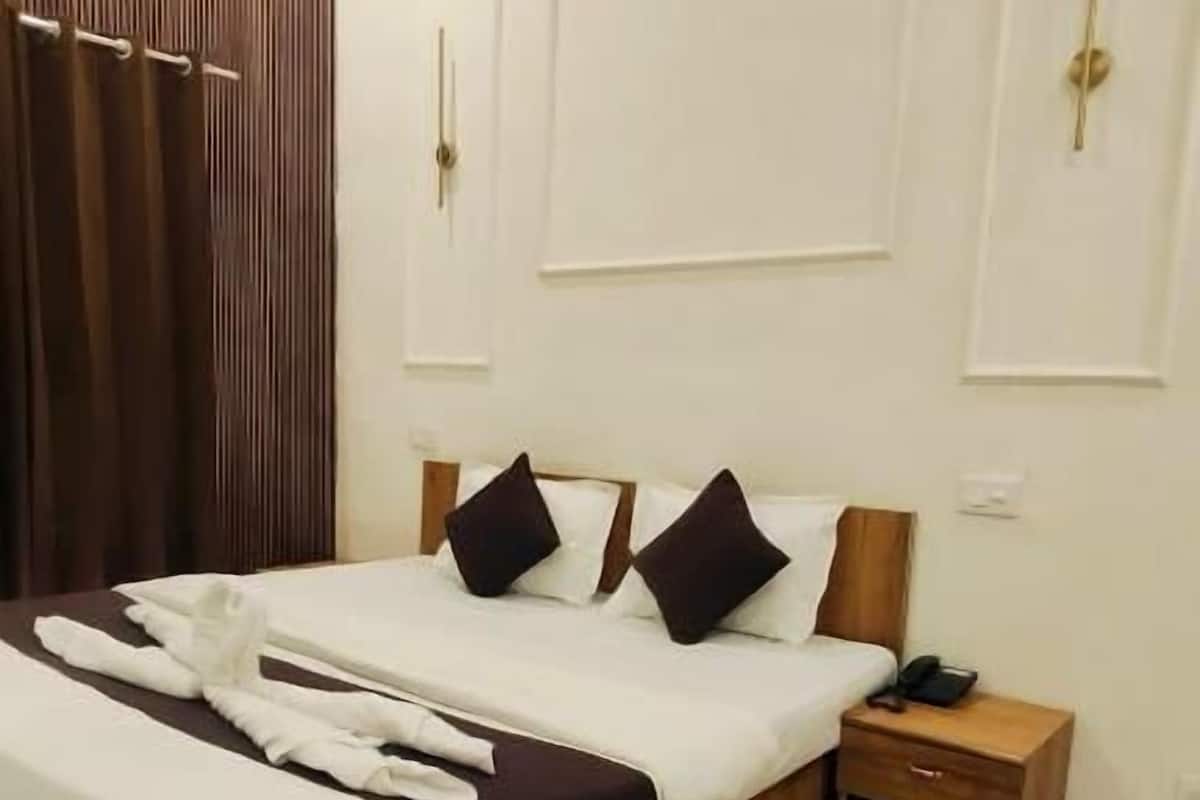 Una habitación de hotel moderna con una cama grande, cabecero de madera y una mesita de noche con teléfono.