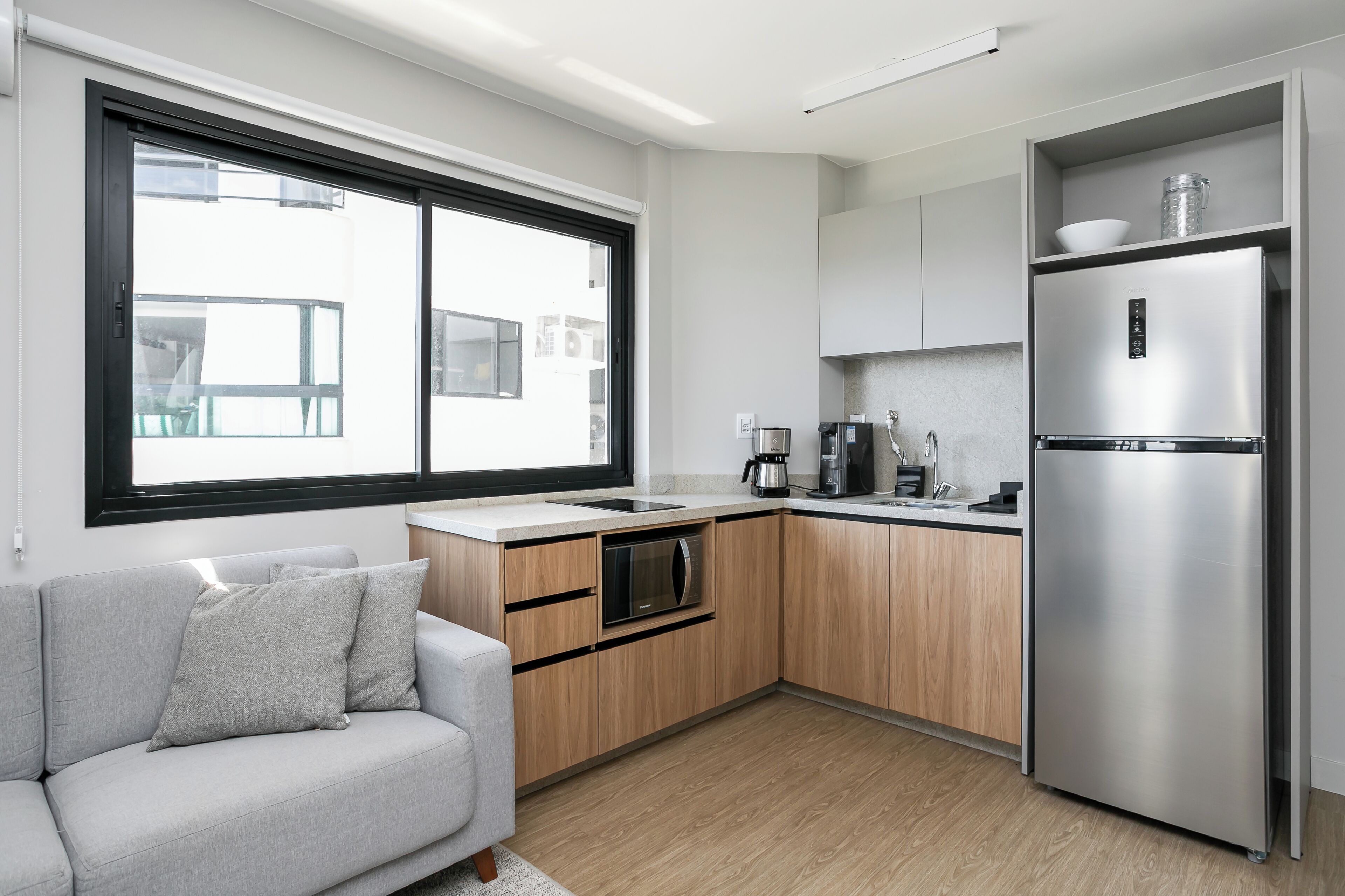 Una cuina moderna amb forn integrat, microones i nevera d'acer inoxidable.
