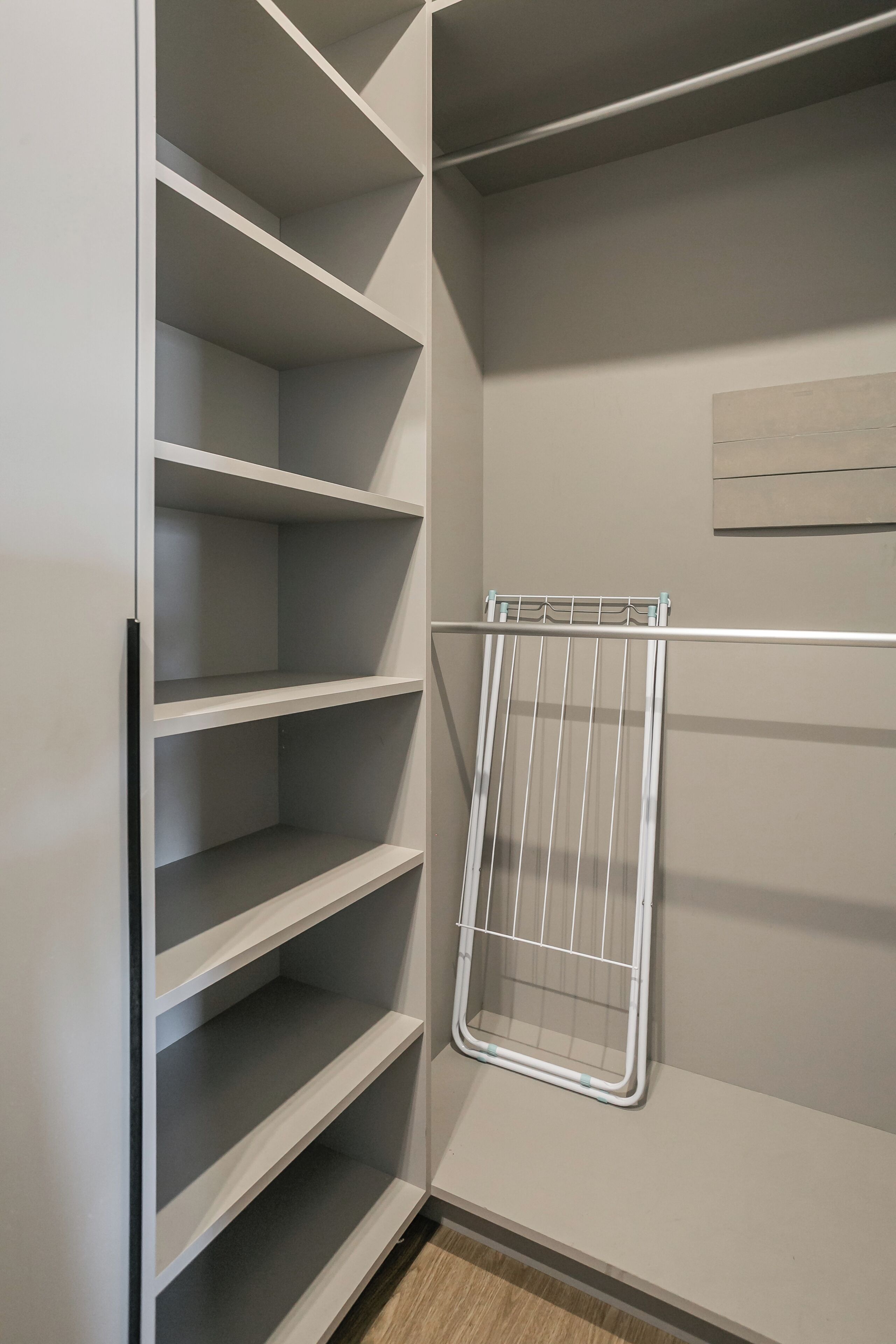 A closet with multiple shelves and a metal drying rack.
