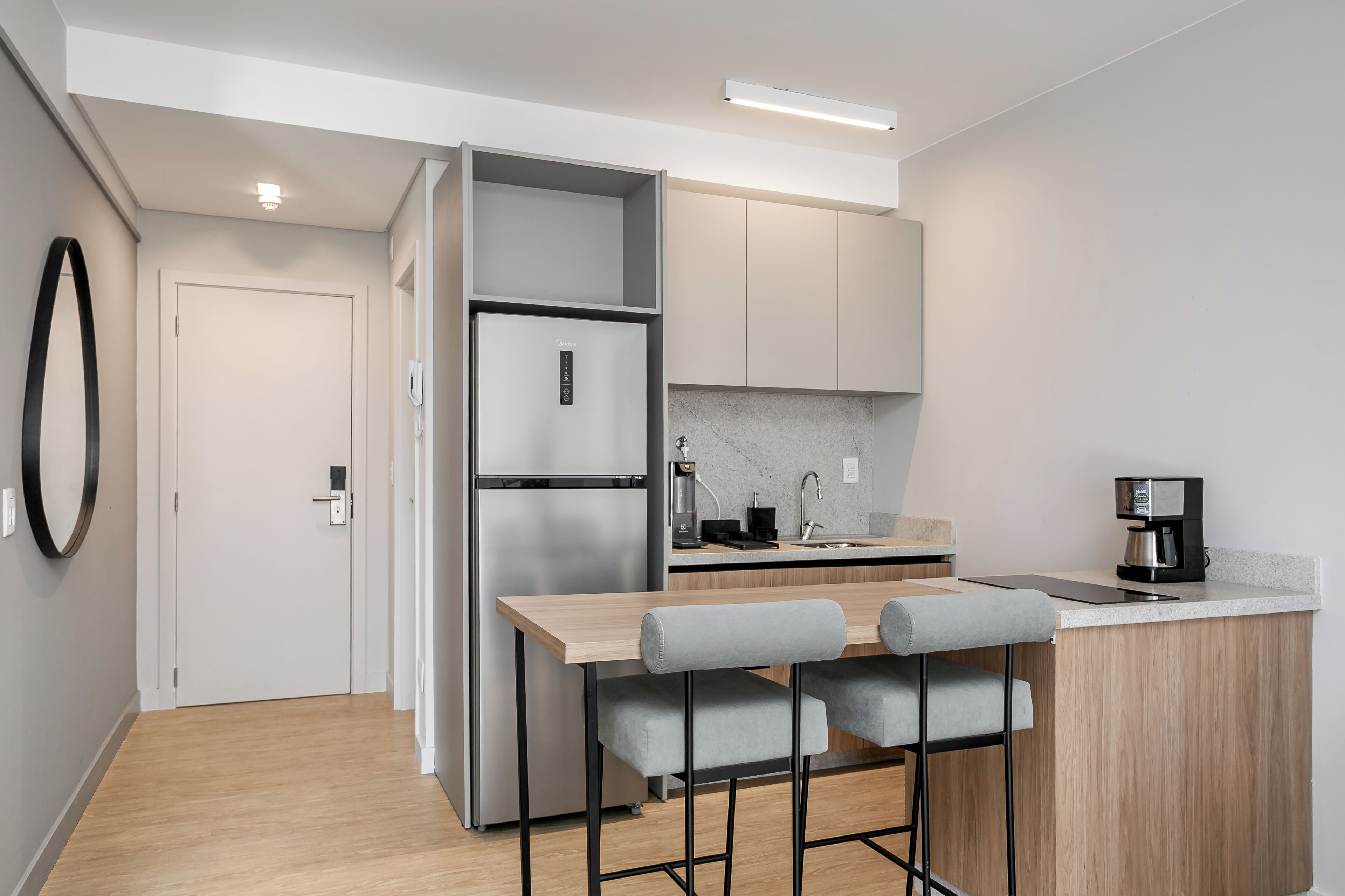 Una cocina moderna con refrigerador empotrado, cafetera y una barra con taburetes.