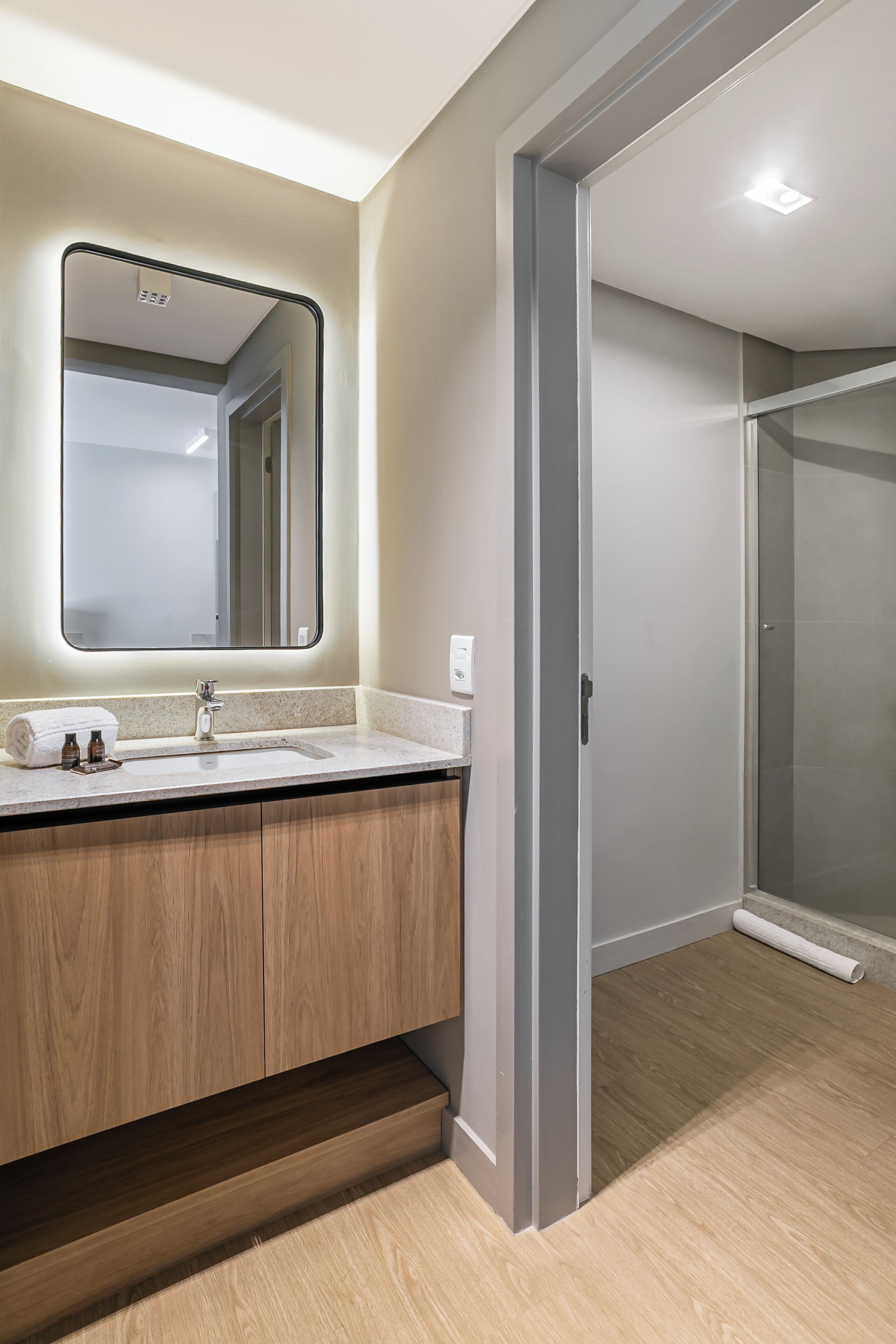 A modern bathroom with a large mirror, a sink, and a shower area.